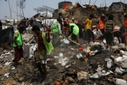Relawan Rohingya membersihkan area setelah kebakaran yang menghancurkan ribuan tempat penampungan di kamp pengungsi Balukhali di Cox's Bazar, Bangladesh, 26 Maret 2021. (Foto: REUTERS/Mohammad Ponir Hossain)