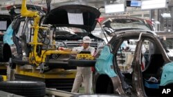 FILE - In this Feb. 19, 2017 photo, a worker prepares to put a spare tire into a Haval SUV H2 model in the Great Wall Motors assembly plant in Baoding in north China's Hebei province. 