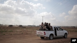 FILE - Palestinian Hamas gunmen ride on the back of a truck as they patrol the border with Israel near the southern Gaza Strip town of Khan Younis, as Israeli military bulldozers are seen in the background, June 10, 2015.