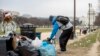 The Capitol building is visible as a man who declined to give his name picks up garbage and stacks it near a trash can during a partial government shutdown on the National Mall in Washington, Dec. 25, 2018. 