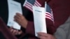 FILE - Participants hold the "Oath of Allegiance" and American flags during a naturalization ceremony at the National Archives in Washington, Dec. 15, 2015.
