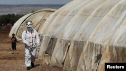 FILE PHOTO: A member of the Syrian Civil defence sanitizes a tent at the Bab Al-Nour internally displaced persons camp, to prevent the spread of coronavirus disease (COVID-19) in Azaz, Syria March 26, 2020. REUTERS/Khalil Ashawi/File Photo