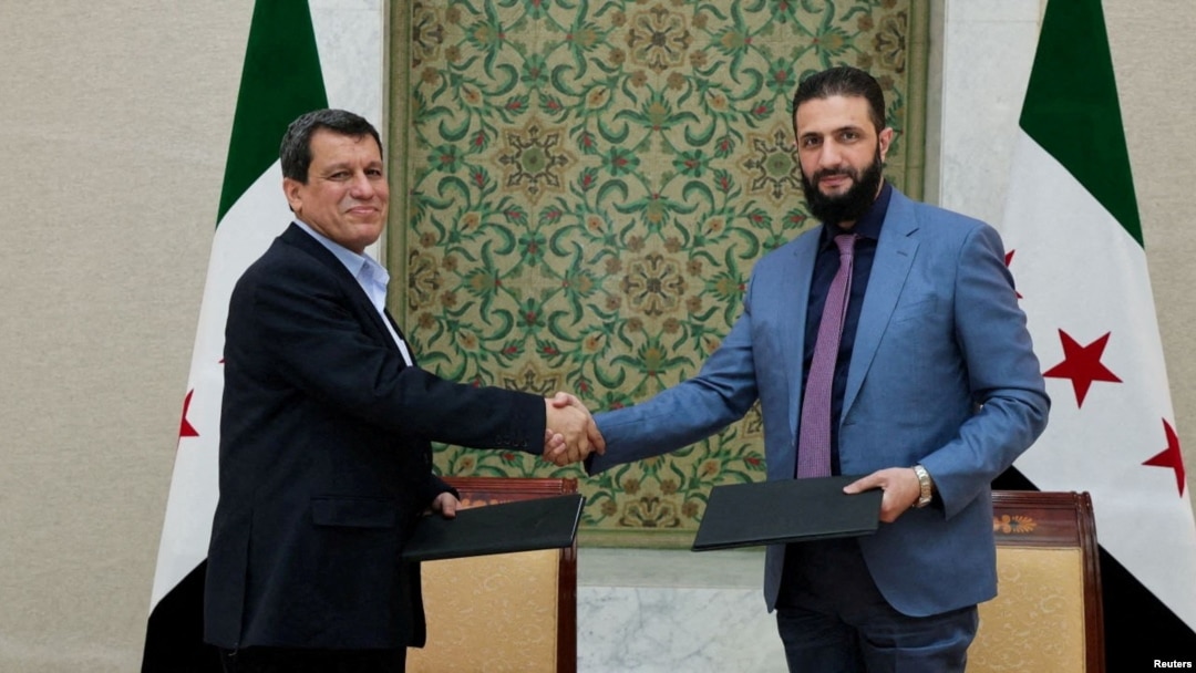 Syria's interim President Ahmed al-Sharaa, right, and commander of Syrian Kurdish-led forces Mazloum Abdi shake hands after reaching a ceasefire and military deal in Damascus, on March 10, 2025. (SANA/Handout via Reuters)