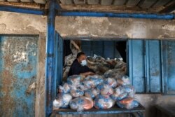 Seorang petugas Palestina menyiapkan kantong persediaan makanan di pusat distribusi bantuan yang dikelola oleh Badan Bantuan dan Pekerjaan PBB (UNRWA), di kamp pengungsi Pantai di Kota Gaza, 7 April 2021. (Foto: REUTERS)
