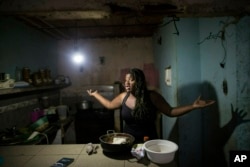 Dugleidi Salcedo complains to a neighbor about the high price of food as she prepares arepas for her three sons in her kitchen in the Petare slum, in Caracas, Feb. 14, 2019.