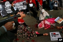 Para demonstran Muslim menggambarkan kekerasan terhadap Muslim Rohingya di Myanmar barat saat demo hari Minggu, 3 September 2017, di Jakarta. (AP Photo/Dita Alangkara)