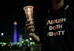 Seorang aktivis memegang lilin dalam doa bersama di luar Istana President, untuk memprotes hukuman mati, 28 Juli 2016.