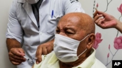 Jose Pereira Lima gets his shot of the COVID-19 vaccine produced by China's Sinovac Biotech Ltd., during the start of the vaccination in elderly people who live in public shelters, in Sao Paulo, Brazil, Jan. 19,