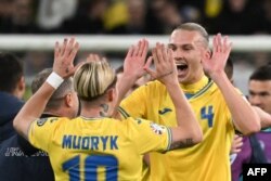 El centrocampista ucraniano #10 Mykhaylo Mudryk y el defensor ucraniano #04 Maksym Talovierov celebran después del partido de fútbol final de clasificación para la EURO 2024 de la UEFA entre Ucrania e Islandia, en Wroclaw, Polonia, el 26 de marzo de 2024. (Foto de Sergei GAP
