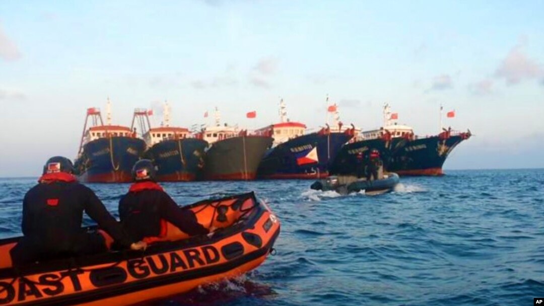 In this handout photo provided by the Philippine Coast Guard, members of the Philippine Coast Guard use rubber boats as they patrol beside Chinese vessels moored at Whitsun Reef, South China Sea, April 14, 2021.