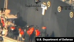 This image released by the Pentagon June 17, 2019, and taken from a U.S. Navy helicopter, shows what the Navy says are members of the Islamic Revolutionary Guard Corps Navy removing an unexploded limpet mine from the M/T Kokuka Courageous.