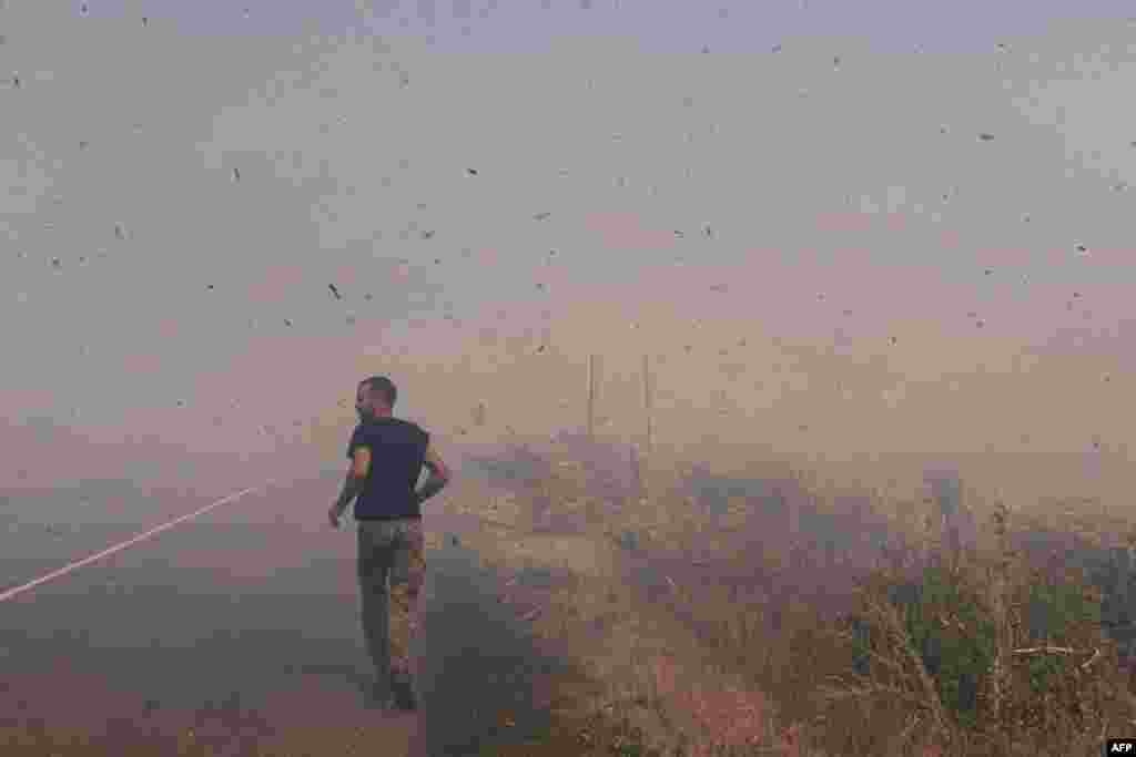 A Ukrainian serviceman runs to help farmers extinguish a burning field near Pokrovsk, Donetsk region, amid the Russian invasion of Ukraine.