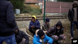 FILE- Migrants wait for food at a camp in Calais, northern France, Oct. 14, 2021. Food sometimes is included in the price smugglers charge to cross.