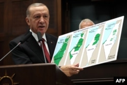 Presiden Turki Recep Tayyip Erdogan memegang peta yang menunjukkan evolusi tanah Israel dan Palestina pada pertemuan partainya di Majelis Agung Nasional Turki di Ankara pada 11 Oktober 2023. (Foto: AFP)