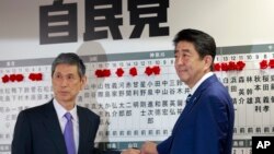 Perdana Menteri Jepang, Shinzo Abe (kanan), pemimpin Partai Demokratik Liberal berfoto bersama Wakil Presiden Masahiko Komura sambil menandai nama-nama politisi yang terpilih dalam pemilihan majelis rendah parlemen di markas Partai LDP di Tokyo, Jepang, 22 Oktober 2017. 