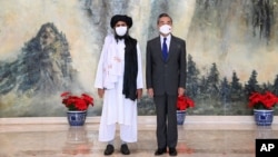 In this photo released by China's Xinhua News Agency, Taliban co-founder Mullah Abdul Ghani Baradar, left, and Chinese Foreign Minister Wang Yi pose for a photo during their meeting in Tianjin, China, July 28, 2021.