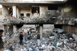 Guards stand on the rubble of a house hit by Saudi-led air strikes in Sanaa, Yemen, January 18, 2022.