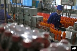 In this Oct. 22, 2018, photo, a worker monitors the production of bottled beverage at Songdowon General Foodstuffs Factory in Wonsan, North Korea.