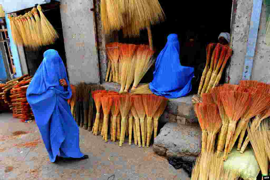 Dua perempuan Afghanistan melihat-lihat sapu yang dijual di toko pinggir jalan di kota Herat.