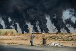 FILE - Smoke billows from burning tires to decrease visibility for Turkish warplanes on the outskirts of the town of Tal Tamr, Syria, along the border with Turkey in the northeastern Hassakeh province, Oct. 16, 2019.