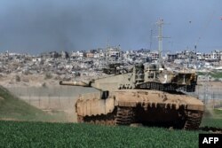 Di sepanjang perbatasan dengan Jalur Gaza pada 18 Januari 2024, terlihat tank Israel meluncur di sepanjang pagar dan merusak bangunan di Gaza. (Foto: AFP)