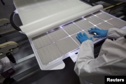 FILE - A production operator checks a panel at the SolarWorld solar panel factory in Hillsboro, Oregon, Jan. 15, 2018.
