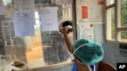 A medical worker checks a person's temperature at the Matanda Hospital in Butembo, Congo, where the first case of Ebola died Feb. 11, 2021, and a second case was recorded in Congo's North Kivu province after a 60-year-old woman died.
