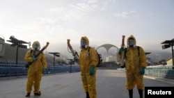 FILE - Municipal workers wait before spraying insecticide at Sambodrome in Rio de Janeiro, Brazil, Jan. 26, 2016.
