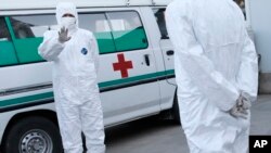 FILE - Medical personnel in protective suits stand by an ambulance at the Sunan International Airport in Pyongyang, North Korea.