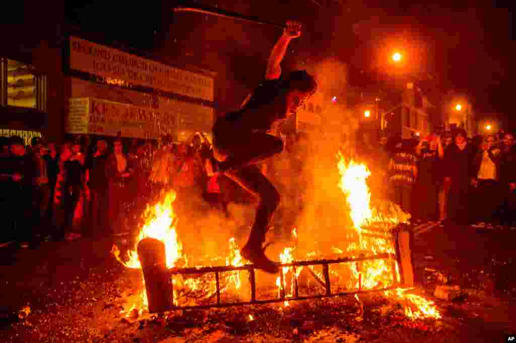 A man jumps over a burning couch in the Mission District after the San Francisco Giants beat the Kansas City Royals to win the World Series, San Francisco, Oct. 29, 2014.