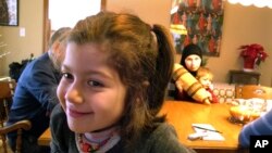 Syrian refugees Dania Khatib, 5, with her mother Mahasen Boshnaq, rear, holding her brother Mohammed, 1, sits in the home of their sponsoring family, Jan. 27, 2017, in Rutland, Vt. The Khatib family arrived in Rutland this month.