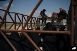 Men, women and children ride in the back of a truck in a convoy evacuating hundreds out of the last territory held by Islamic State militants in Baghuz, eastern Syria, Feb. 22, 2019. Small trucks carrying disheveled men, women and children left the Islamic State group's last pocket of territory in eastern Syria in an escorted convoy on Friday, hours after coalition airstrikes meant to pressure the militants targeted the area on the banks of the Euphrates River.