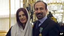 FILE - Iranian film director Asghar Farhadi and his wife, Parisa, pose after he was awarded the Officer of the Order of Arts and Letters medal, at the French Ministry of Culture, in Paris, France, Feb. 27, 2014.