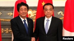 日本首相安倍晉三在東京與到訪的中國總理李克強握手。（2018年5月9日）