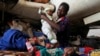 A Central African woman displaced by inter-communal violence takes care of her twin baby boys at a camp for displaced persons at Bangui M'Poko International Airport, Feb. 11, 2014.
