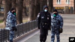 FILE - Police officers wearing face masks patrol at Patriarch Ponds in Moscow, Russia, April 22, 2020.