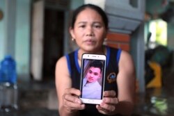 Hoang Thi Ai holds up her phone showing a photo of her son, Hoang Van Tiep, who she fears is one of the possible victims in the truck deaths in England, at her home in Dien Chau district, Nghe An province, Vietnam, Oct. 28, 2019.