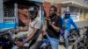 Jimmy Cherizier, the leader of the "G9 et Famille" gang, talks with members of his gang while taking a ride on the back of a motorcycle in his district of Delmas 6 in Port-au-Prince, Haiti, Jan. 24, 2023. 