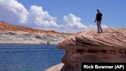 Bill Schneider berdiri di Danau Powell, 31 Juli 2021, dekat Page, Arizona. Musim panas ini, ketinggian air mencapai titik terendah bersejarah di tengah perubahan iklim di AS Barat. (Foto: AP/Rick Bowmer)