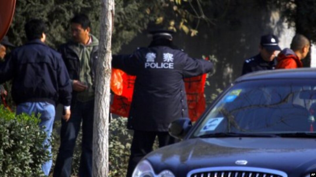 A policeman looks at a banner that a supporter of dissident Chinese artist Ai Weiwei tried to display outside the artist's house in Beijing, November 14, 2011.