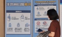 A visitor wearing a face mask walks near a banner showing precautions against the coronavirus at the Gyeongbok Palace, one of South Korea's well-known landmarks, in Seoul, South Korea, Aug. 16, 2020.