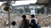 Rain, Satria, dan Cepi memandangi pemukimannya yang telah digusur, sesaat sebelum berangkat sekolah, Senin (16/12) siang. (VOA/Rio Tuasikal)