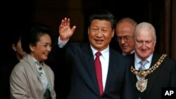 China's President Xi Jinping, center, waves as he leaves after lunch with Britain's Prime Minister David Cameron at Manchester Town Hall in Manchester, England, Oct. 23, 2015.