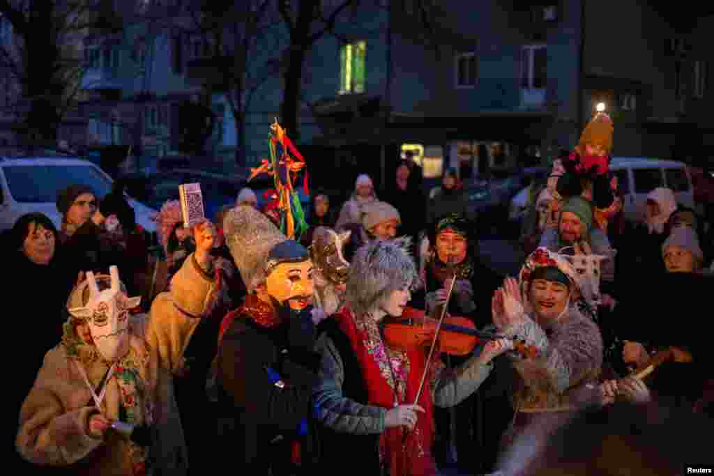 Revelers play folk music and wear traditional costumes designed to ward off evil spirits and bring good fortune for the next year, during a Malanka Ukrainian folk celebration in a courtyard in Kyiv, Ukraine.