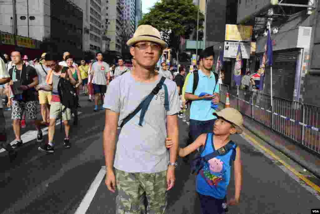 香港市民黃先生帶同9歲的兒子參加7-1大遊行,希望爭取真普選,他認為是漫長的道路。(美國之音湯惠芸拍攝)