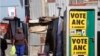 A woman, left, passes a poster for African National Congress, ANC, in Khayelitsha township outside Cape Town, South Africa, Aug. 1, 2016. South Africa's ruling party faces a significant challenge in Wednesday's municipal elections.