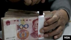 Seorang pegawai bank di Tiongkok sedang menghitung sejumlah yuan. Mata uang ini menjadi incaran investasi setelah jebloknya dolar.