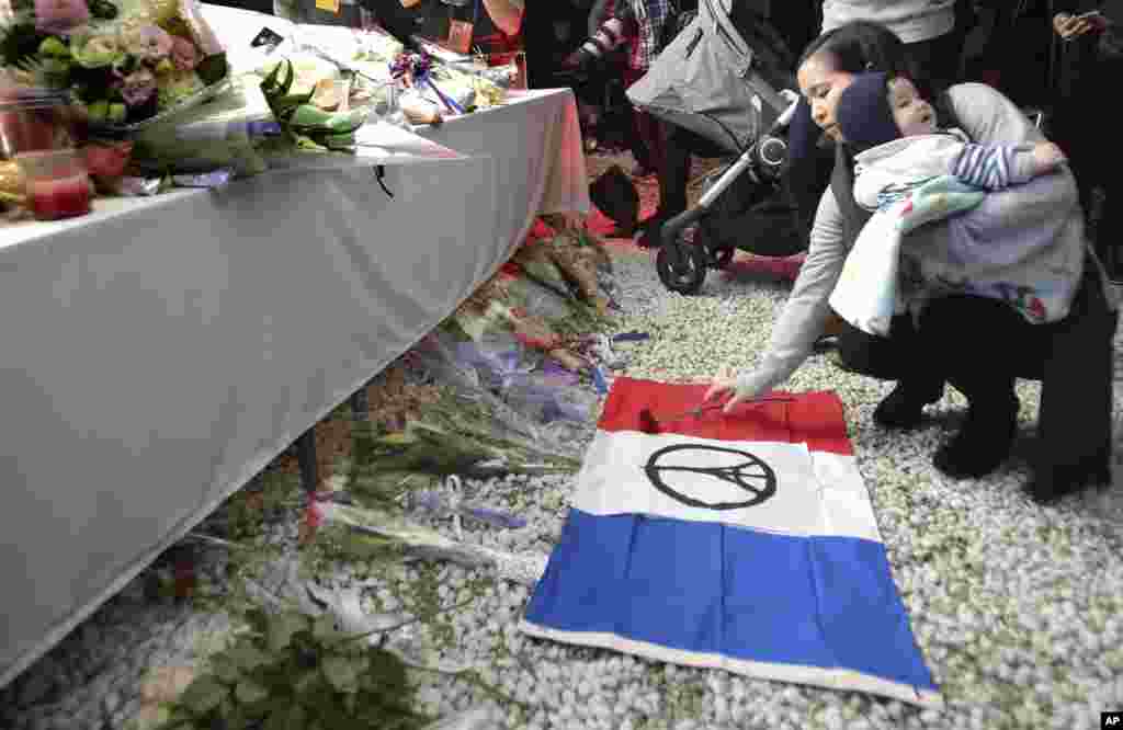 Seorang perempuan menaruh setangkai bunga dalam doa bersama bagi para korban serangan maut di Paris, di Kedutaan Besar Perancis di Tokyo (15/11). (AP/Shizuo Kambayashi)