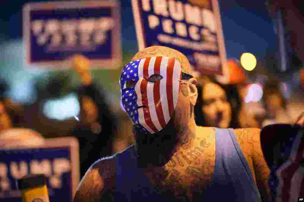 Elongi azipi na masque ya bendele ya mboka, moko na bayi Trump azali kati na milulu ya botelemeli na Las Vegas, Nevada, 4 novembre 2020.. (AP Photo/John Locher)