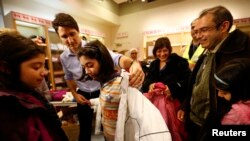 Perdana Menteri Kanada Justin Trudeau membantu pengungsi muda Suriah mengenakan jaket musim dingin setelah tiba bersama keluarganya dari Beirut di bandara internasional Toronto Pearson di Mississauga, Ontario, Kanada, 11 Desember 2015. (foto: dok.) 